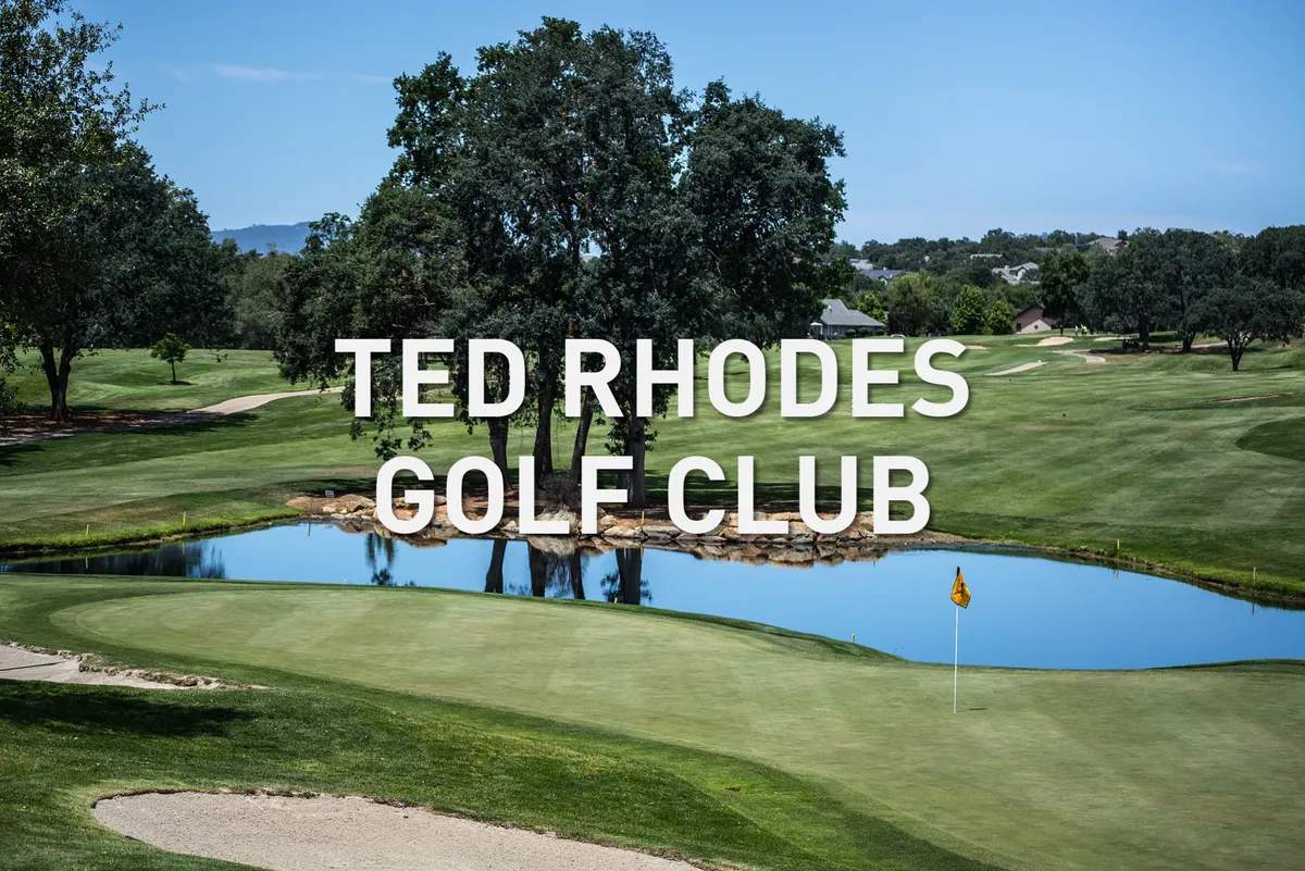 A scenic view across a manicured golf course with a pond reflecting the surrounding trees and a flag marking the green. The setting is tranquil, inviting guests to envision rounds of golf or quiet moments enjoying the landscape.