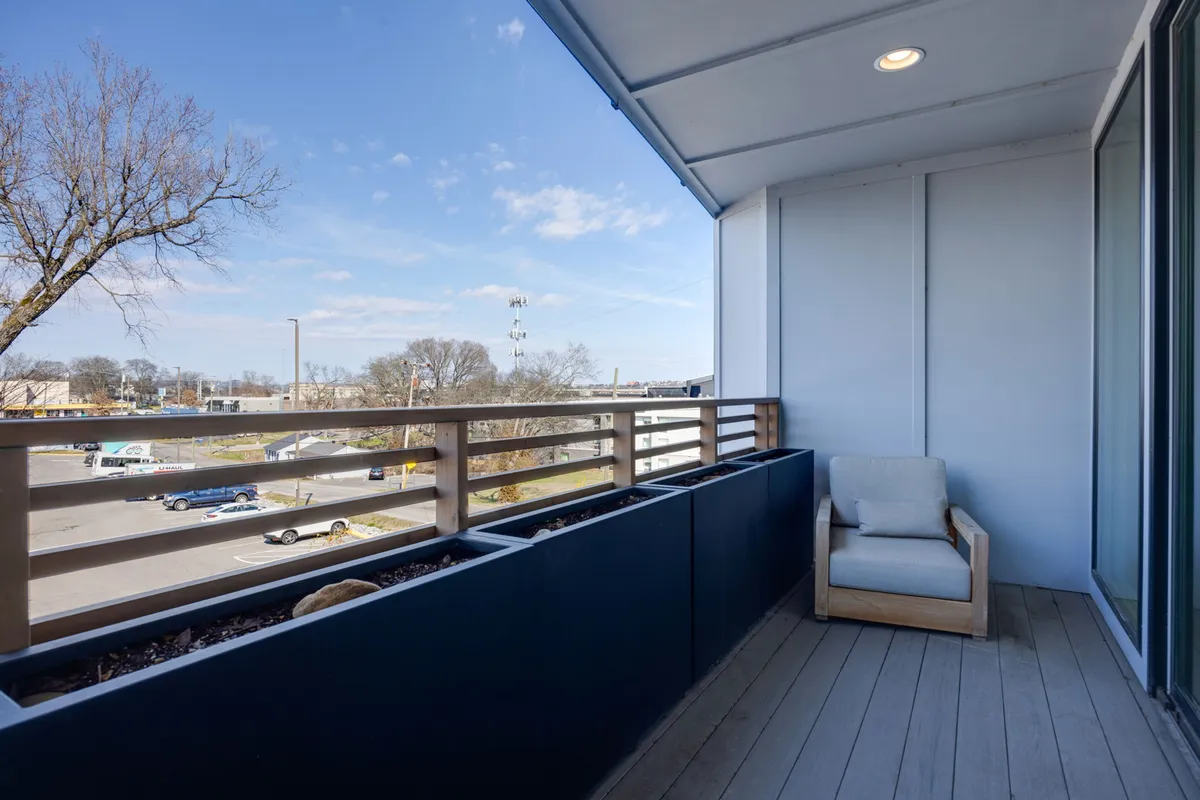 A tranquil exterior balcony scene featuring comfortable outdoor seating, potted plants, and a railing overlooking the city. The setting invites relaxation—perfect for unwinding after a lively night out in Nashville’s music district.
